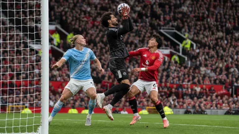 Een doelman en drie spelers in actie voor het doel tijdens een Manchester-derby.