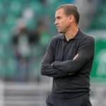 Michiel Jonckheere in donker bovenstuk langs de zijlijn van een voetbalveld.