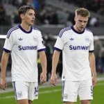 Twee Anderlecht-spelers wandelen na de wedstrijd over het veld.