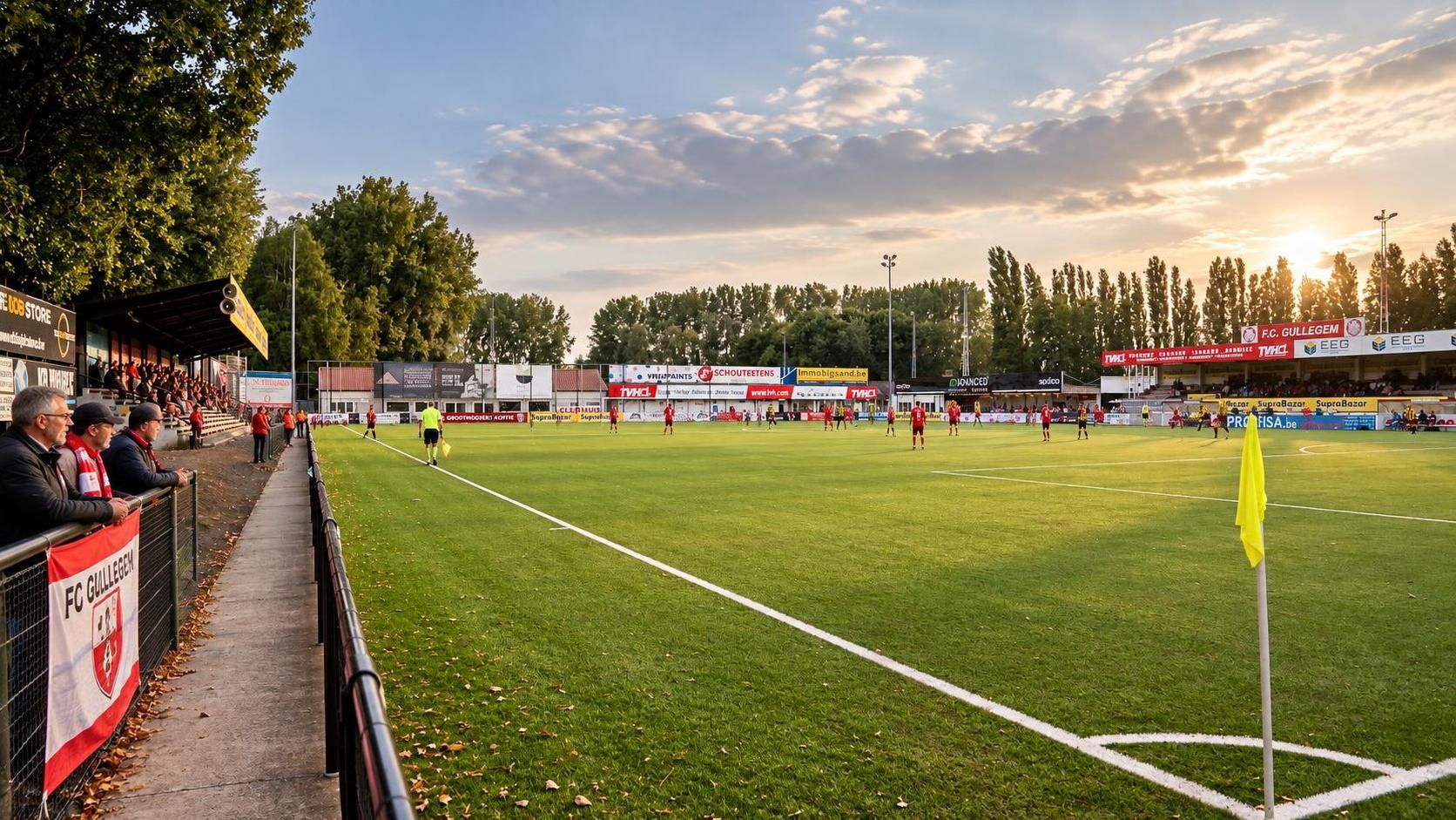FC Gullegem in het rood en wit bij het compacte Poezelhoek Stadion, met speelveld en hoofdtribune als herkenbare dorpssetting.