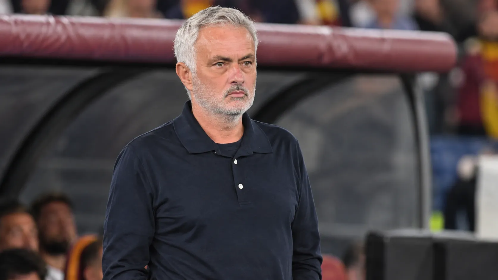 José Mourinho in een donker poloshirt naast de technische zone van een voetbalstadion.