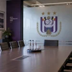 Lege vergaderzaal van Anderlecht met het clubembleem op een glazen wand.
