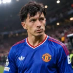 Lisandro Martínez in het blauwe shirt van Manchester United aan de zijlijn van een stadion.