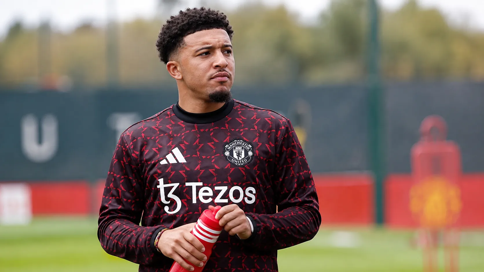 Jadon Sancho drinkt water tijdens een warming-up in Manchester United-kleding.