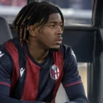 Samuel Mbangula zit geconcentreerd op de bank in een Bologna-dug-out.