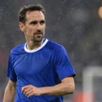 Sven Kums in blauw tenue op een regenachtig Europees voetbalveld.