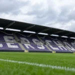 Lege paars-witte zitjes op een tribune van het Kiel met de naam Beerschot zichtbaar.