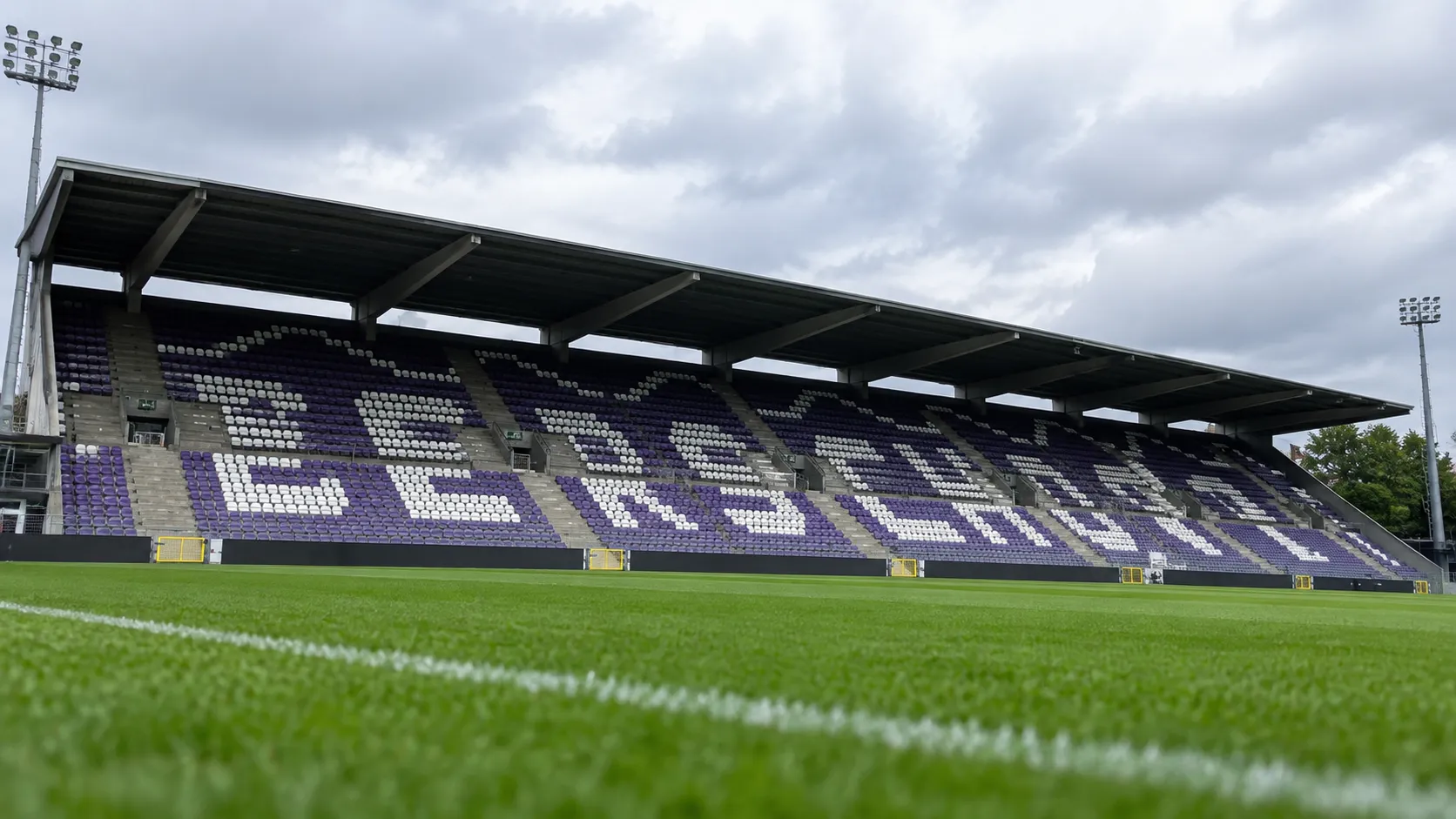 Lege paars-witte zitjes op een tribune van het Kiel met de naam Beerschot zichtbaar.