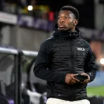 Francis Amuzu langs de zijlijn in een zwarte jas van RSC Anderlecht.