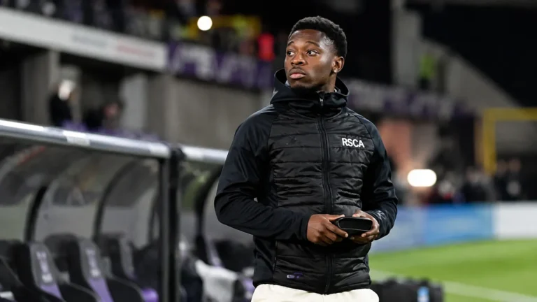 Francis Amuzu langs de zijlijn in een zwarte jas van RSC Anderlecht.