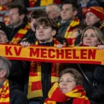 Een groep KV Mechelen-supporters met sjaals in de tribune.