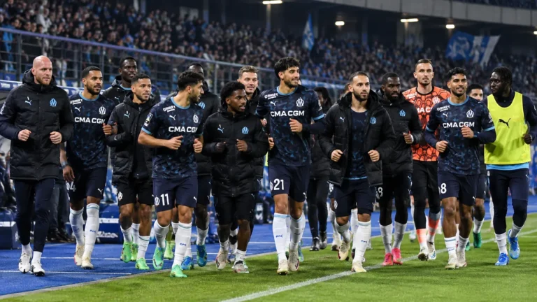 Een groep spelers en stafleden van Olympique Marseille in donkere clubkleding tijdens de warming-up.