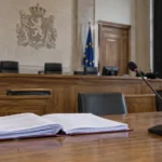 Een lege zittingszaal met een dossier en microfoon voor een procedurele behandeling.