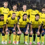 Een groep Union-spelers in gele wedstrijdshirts poseert op het veld in een Europees stadion.