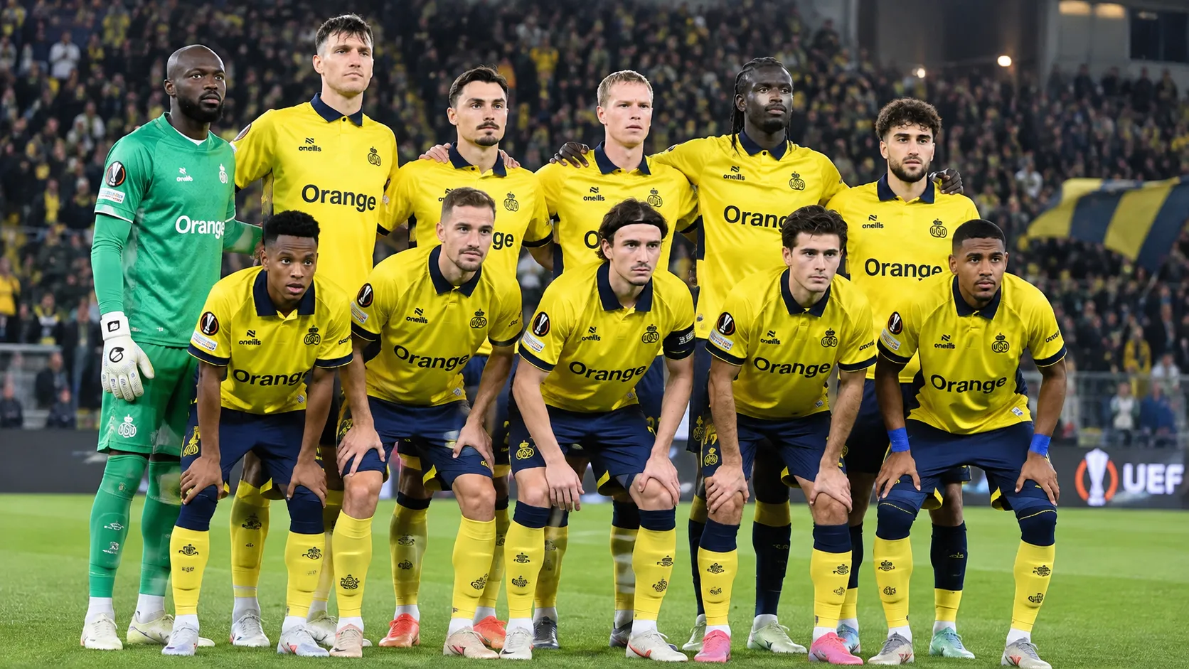 Een groep Union-spelers in gele wedstrijdshirts poseert op het veld in een Europees stadion.