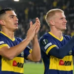 Twee voetballers in donkerblauw-geel tenue applaudisseren na een Europese wedstrijd.