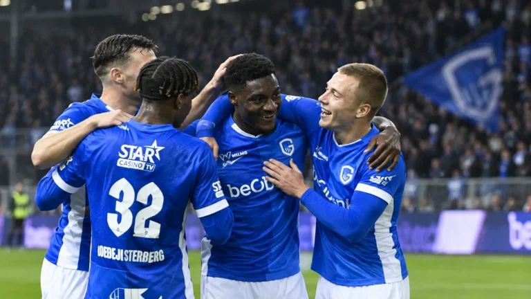 Een groep voetballers in blauwe shirts viert samen op het veld.