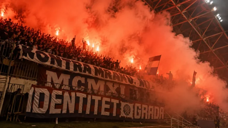 Groep Hajduk Split-supporters met spandoeken in een rood-oranje rookgordijn op de tribune.