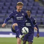 Een Anderlecht-speler in paars wedstrijdtenue tijdens een wedstrijdmoment op het veld.