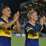 Twee STVV-spelers in blauw-geel tenue applaudisseren na de wedstrijd in het stadion.