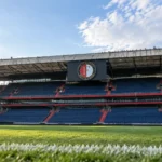 Lege tribune en grasveld in een Feyenoord-stadion met een vast clubembleem.