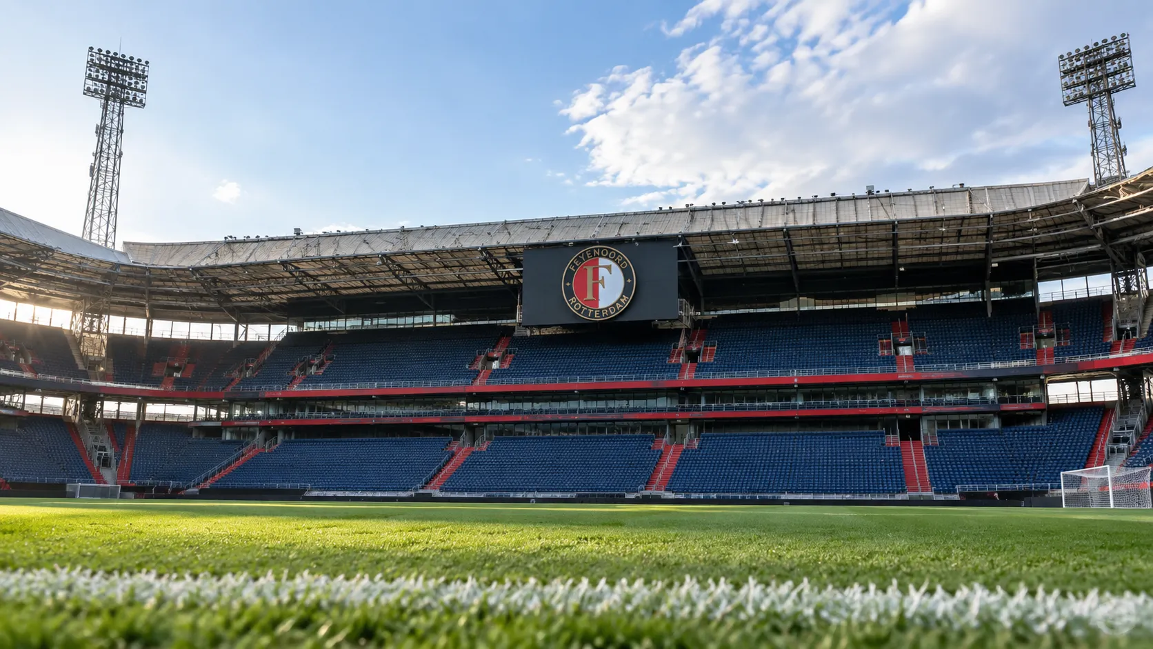 Lege tribune en grasveld in een Feyenoord-stadion met een vast clubembleem.