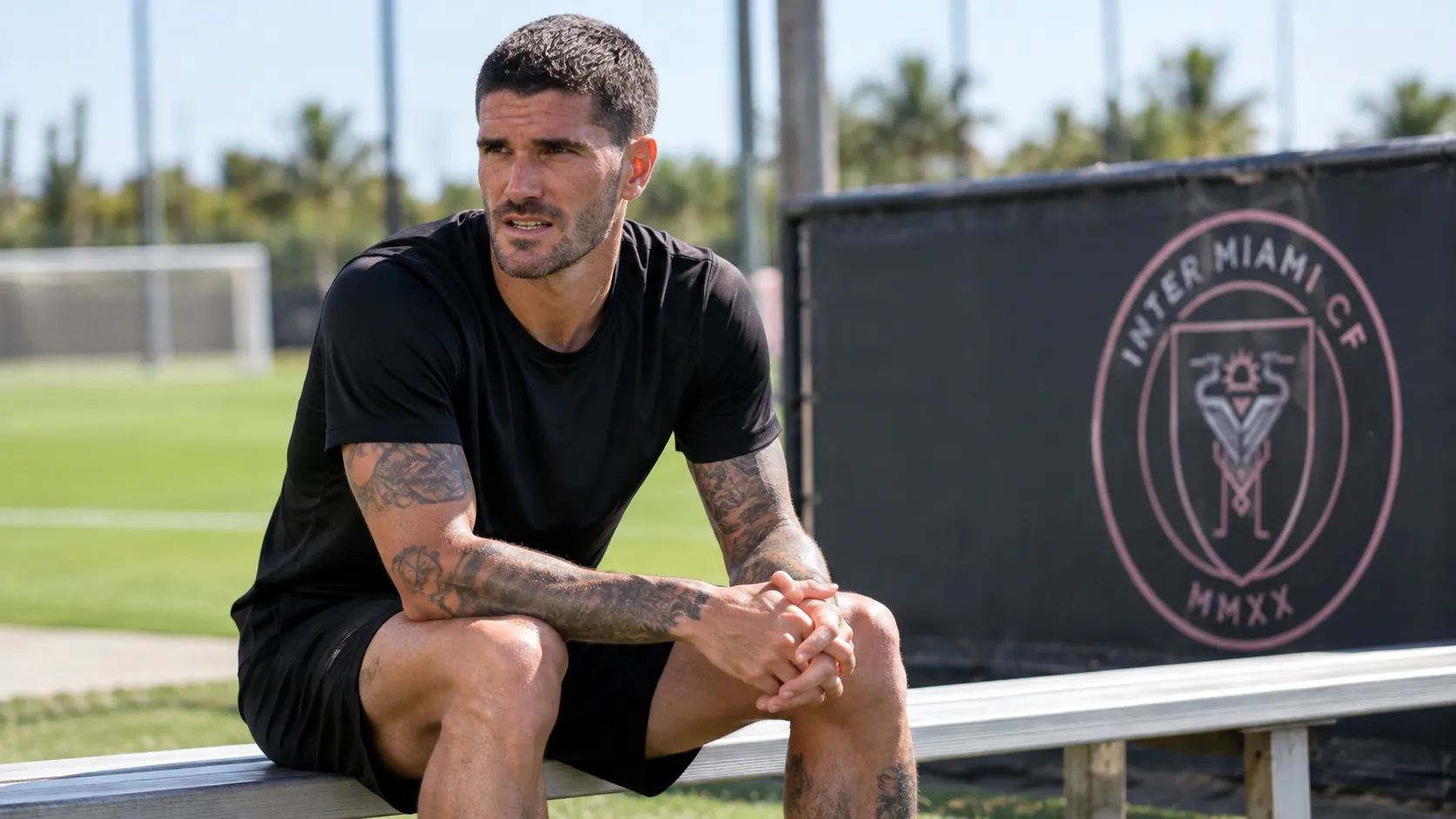 Rodrigo De Paul zit na een training alleen op een bankje naast het trainingsveld van Inter Miami FC.