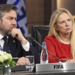 Twee voetbalofficials luisteren in een FIFA Council-vergaderzaal.