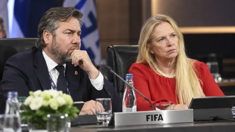 Twee voetbalofficials luisteren in een FIFA Council-vergaderzaal.