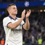 Nicolò Tresoldi in het witte shirt van Club Brugge terwijl hij na een wedstrijd naar de tribunes applaudisseert.