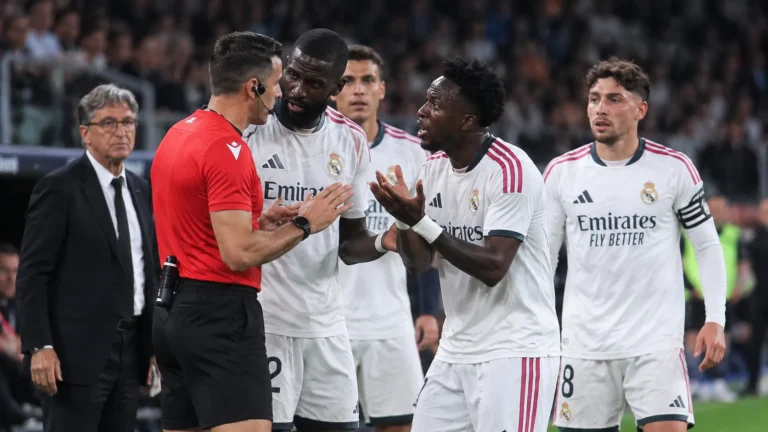 Een groep Real Madrid-spelers bespreekt een beslissing met een scheidsrechter langs het veld.
