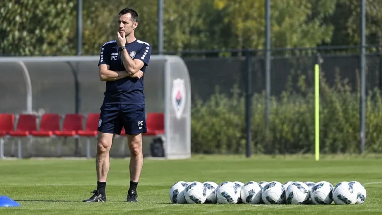 Een staflid van Antwerp in trainingskleding op het trainingsveld met voetballen.