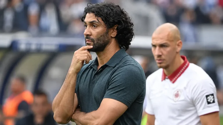 Marvin Compper staat geconcentreerd langs de zijlijn met een speler op de achtergrond.