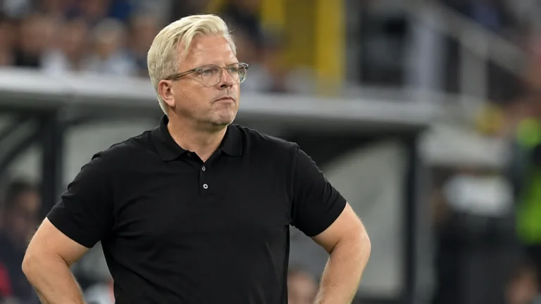 Lars Friis aan de zijlijn van een voetbalstadion in een zwart poloshirt.