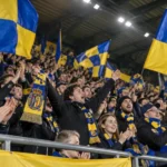 Supporters van SK Beveren zwaaien met blauw-gele vlaggen op de tribune.
