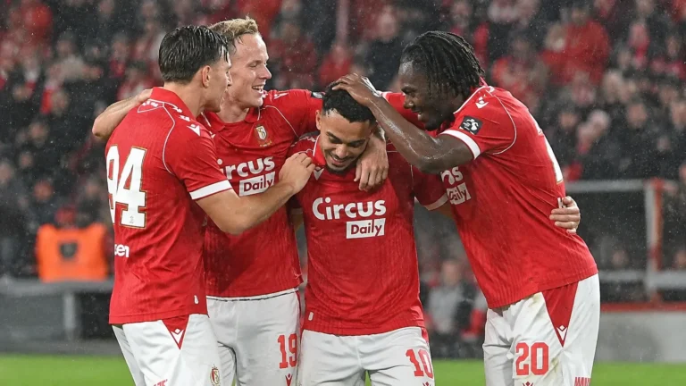 Een groep spelers van Standard viert samen op het veld tijdens een regenachtige bekerwedstrijd.