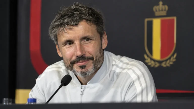 Mark van Bommel aan een persconferentietafel met een Belgisch nationaal ploegembleem op de achtergrond.