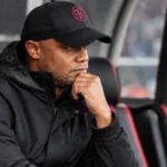 Vincent Kompany zit geconcentreerd in de technische zone langs een voetbalveld.