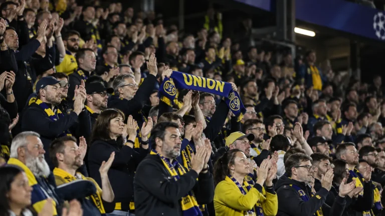 Supporters van Union applaudisseren in de tribune met een blauw-gele sjaal.