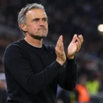 Een PSG-coach applaudisseert langs de zijlijn tijdens een avondwedstrijd.