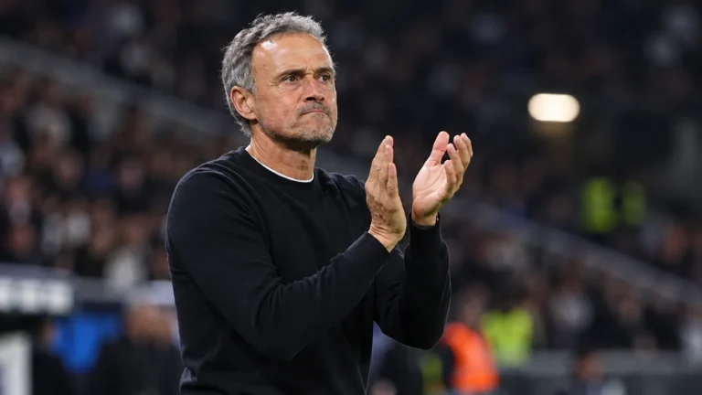 Een PSG-coach applaudisseert langs de zijlijn tijdens een avondwedstrijd.
