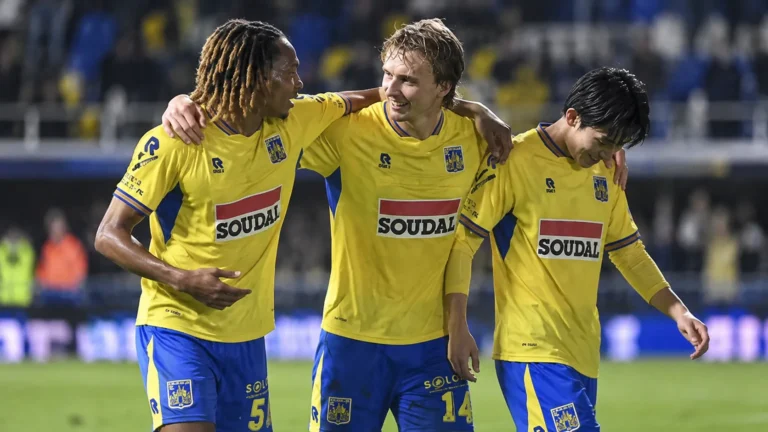 Drie spelers van KVC Westerlo in geel-blauwe wedstrijdkleding vieren samen na een match.