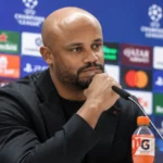 Vincent Kompany spreekt op een persconferentie achter een microfoon.