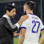 Een medewerker van Anderlecht spreekt na de wedstrijd op het veld met een speler in een wit-paars shirt.