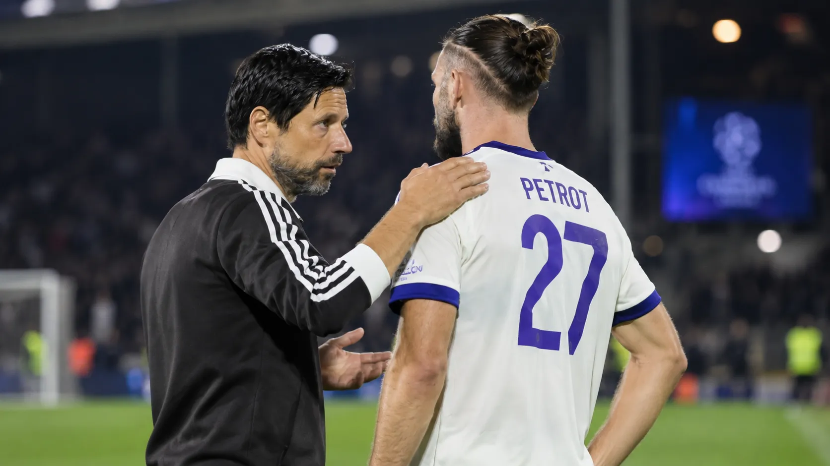 Een medewerker van Anderlecht spreekt na de wedstrijd op het veld met een speler in een wit-paars shirt.