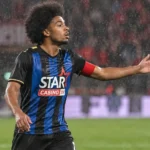 Een speler in een zwart-blauw gestreept tenue tijdens een regenachtige wedstrijd op Sclessin.