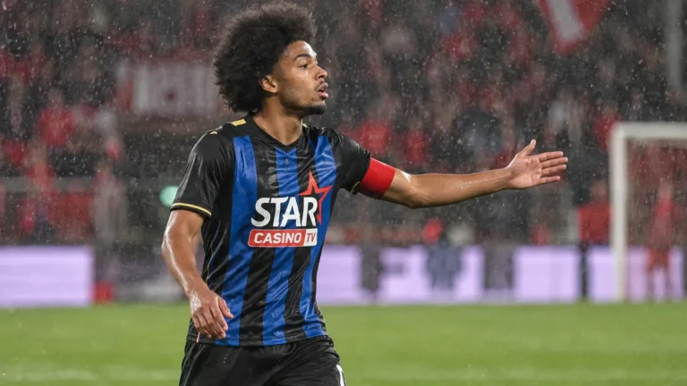 Een speler in een zwart-blauw gestreept tenue tijdens een regenachtige wedstrijd op Sclessin.