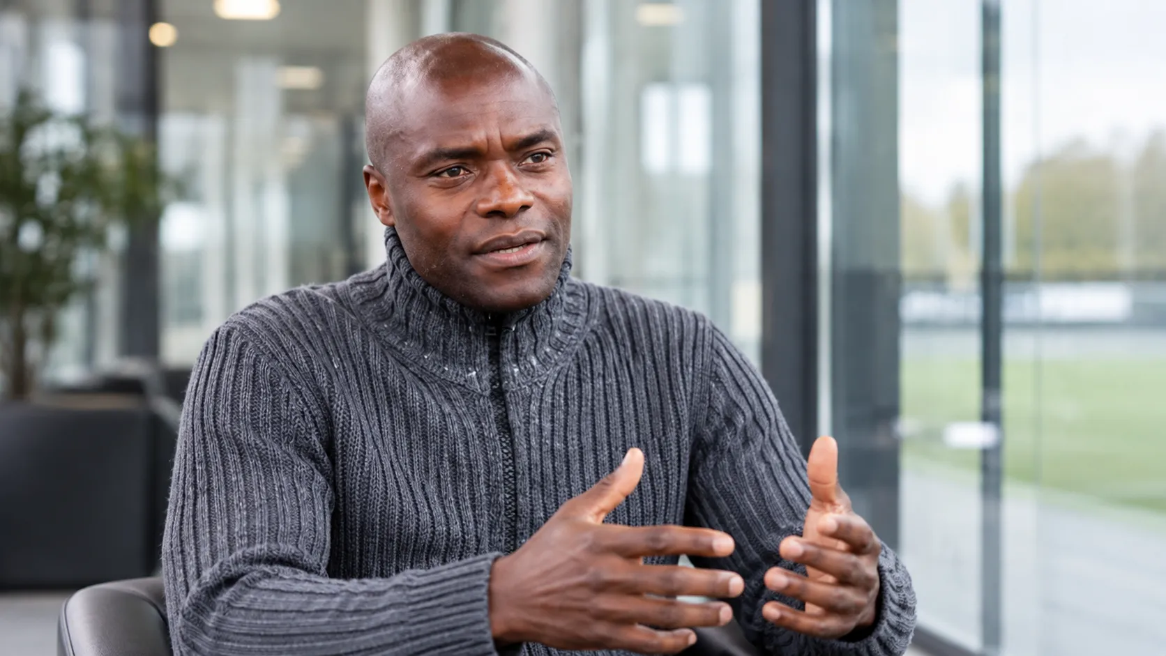 Mbo Mpenza tijdens een interview in een rustige voetbalmediaomgeving.