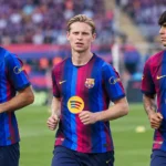 Drie Barcelona-spelers in gestreepte shirts tijdens een gezamenlijke opwarming op het veld.