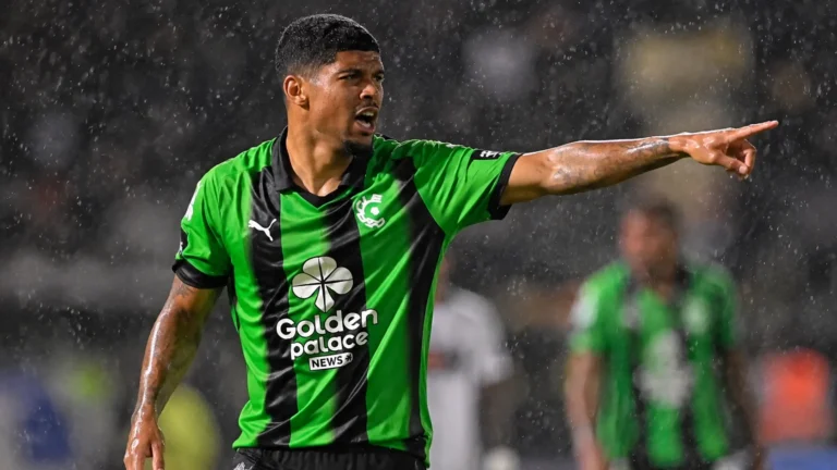 Een Cercle Brugge-speler in groen-zwart tenue gebaart op een nat voetbalveld.